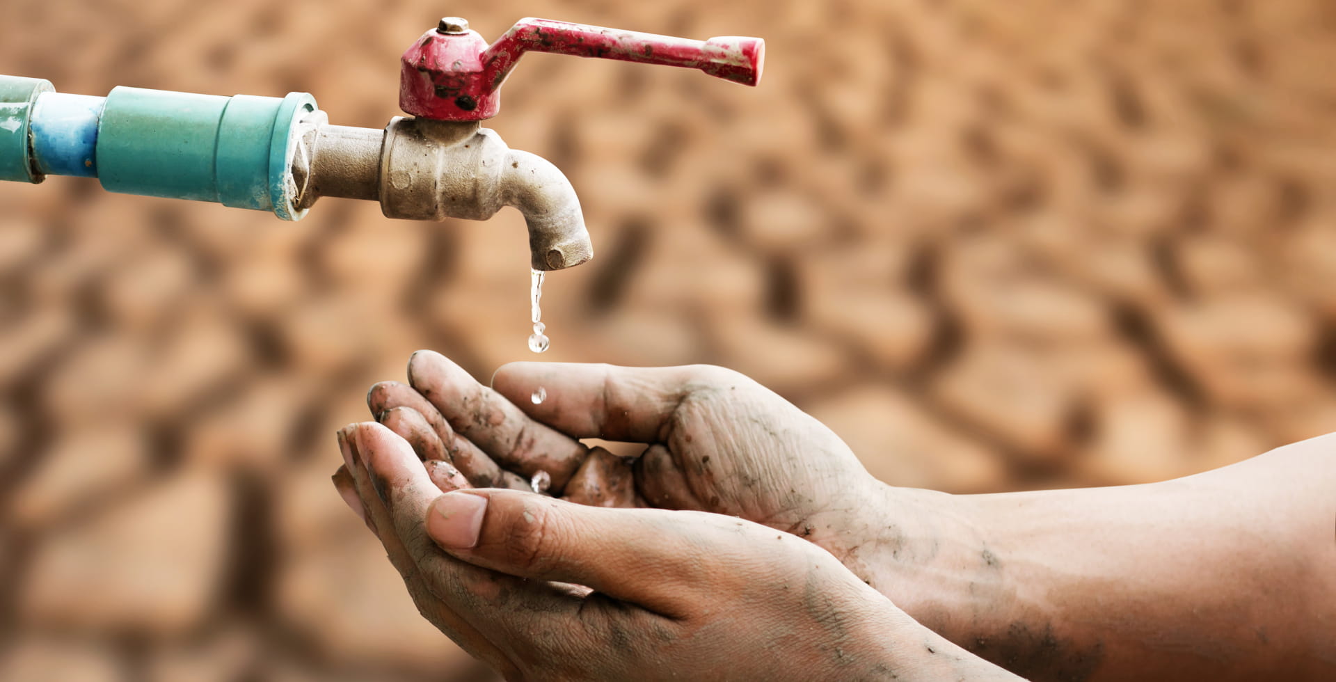 Hand of people wating for a drip of water from a faucet at desert. Climate change, water scarcity and crisis concept.